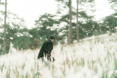 Man standing on field against trees
