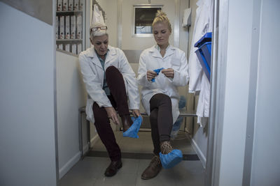 Two lab technicians putting on sterile protective clothing