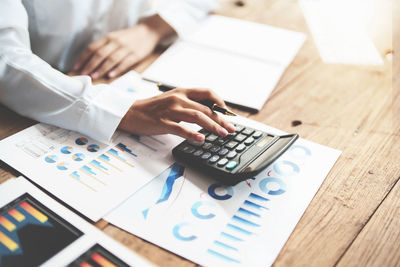 Midsection of businessman using calculator on table