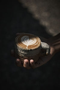 Close-up of hand holding coffee on table