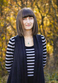 Portrait of smiling young woman standing in autumn