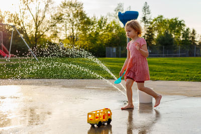 Small child playing at splash pad playground in summer. water park with fountains for children