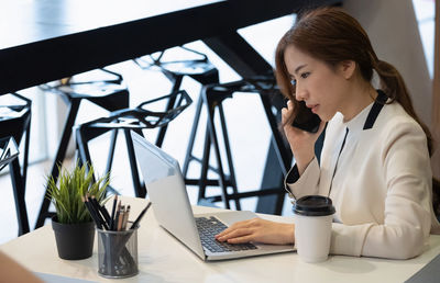 Woman using mobile phone while sitting on table
