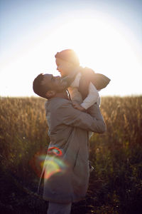 Father and son are standing on a field with dry grass outside the city in autumn