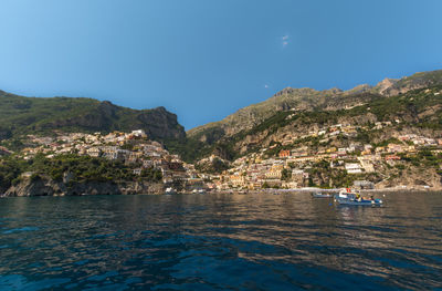 Scenic view of sea and mountains against clear blue sky