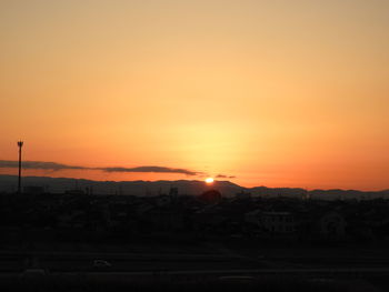 Silhouette city against orange sky