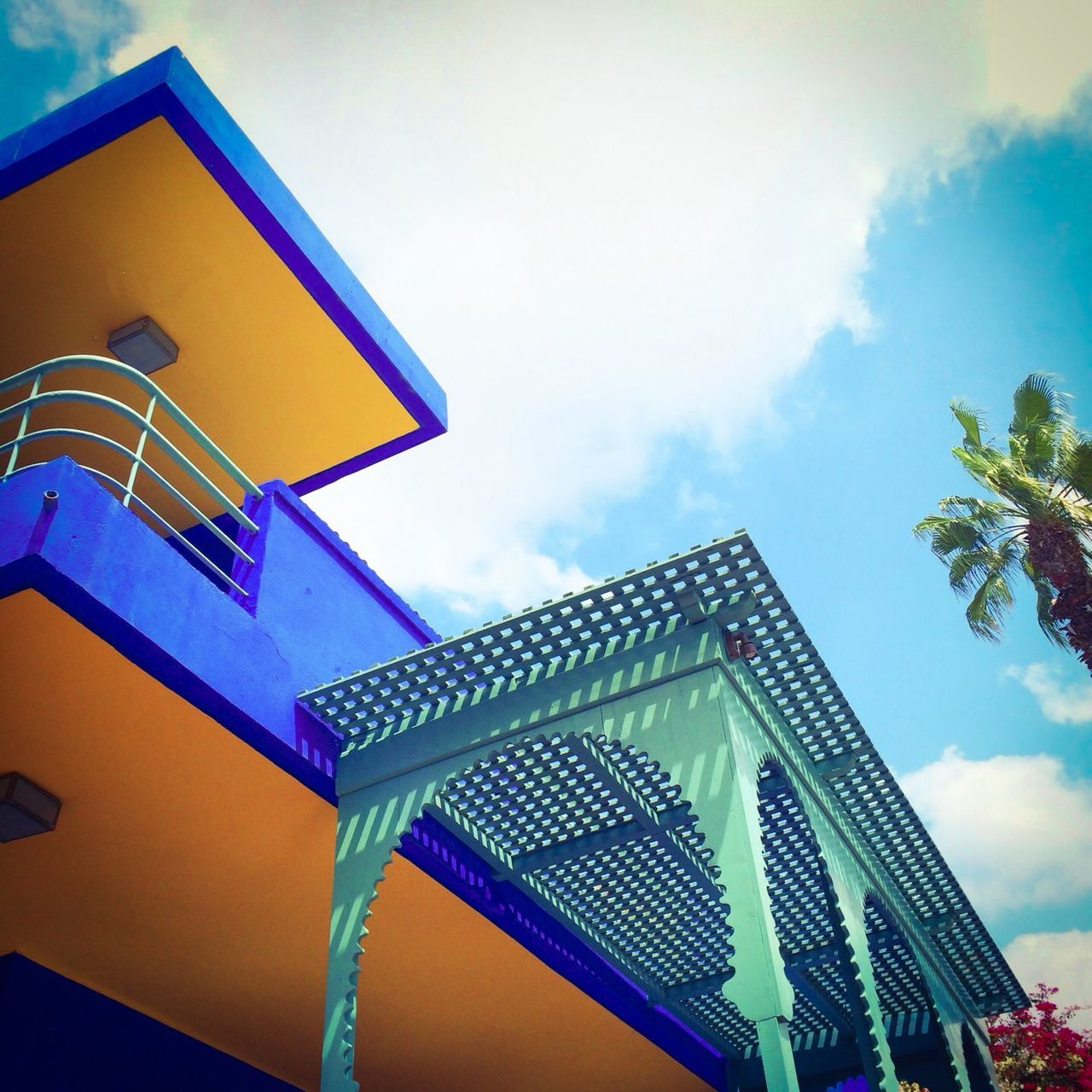 low angle view, architecture, built structure, building exterior, sky, blue, multi colored, cloud - sky, cloud, building, day, outdoors, high section, no people, pattern, art and craft, window, cloudy, house, design