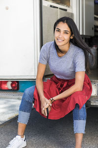 Portrait of confident young female owner sitting at food truck entrance