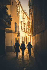 Rear view of people walking on sidewalk in city