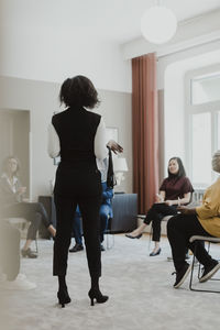 Rear view of businesswoman giving presentation to male and female employee at education class