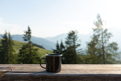 Tin mug on the wooden bench on the mountains background. hiking concept