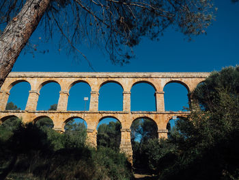 Low angle view of arch bridge against clear blue sky