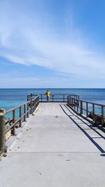 Rear view of man on pier over sea against sky