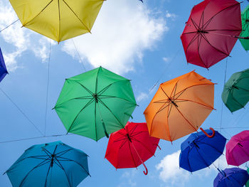 Low angle view of multi colored umbrellas hanging against blue sky