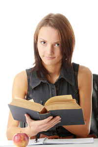 Portrait of young woman reading book against white background