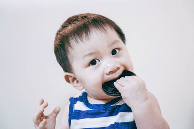 Portrait of cute baby boy holding toy against white background