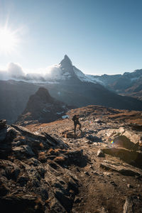 Scenic view of mountains with man standing on rocks against sky