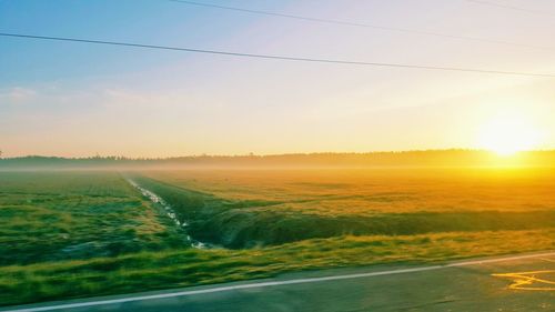 Scenic view of agricultural field against sky during sunset