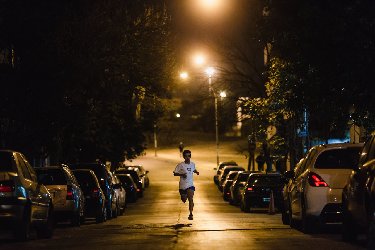 VEHICLES ON ROAD AGAINST ILLUMINATED STREET AT NIGHT