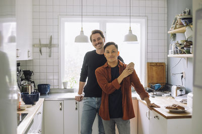 Portrait of smiling multiracial gay couple standing in kitchen at home