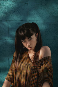 Portrait of a young woman sitting against wall