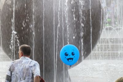 Rear view of boy standing against blue water