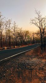 Road amidst trees against sky during sunset