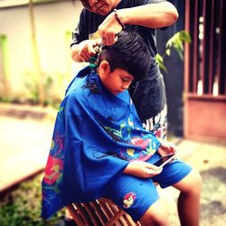 Mother hair dressing baby sitting outdoors