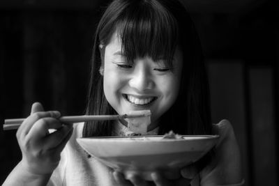 Smiling woman eating food with chopsticks