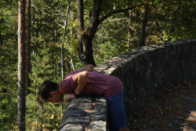 Rear view of men sitting on tree trunk in forest