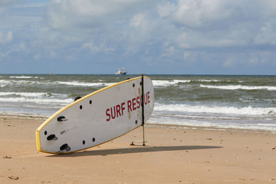Information sign on beach against sky