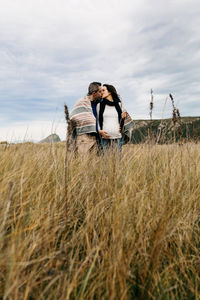 Pregnant woman kissing man on grassy field