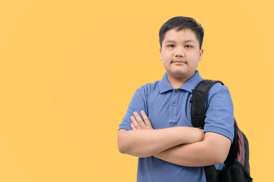 Portrait of boy standing against orange background