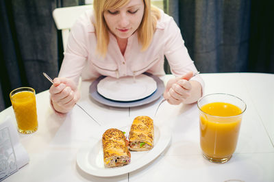 Young woman having food and drink while sitting at home