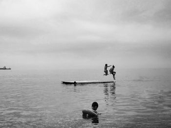 Men in sea against sky