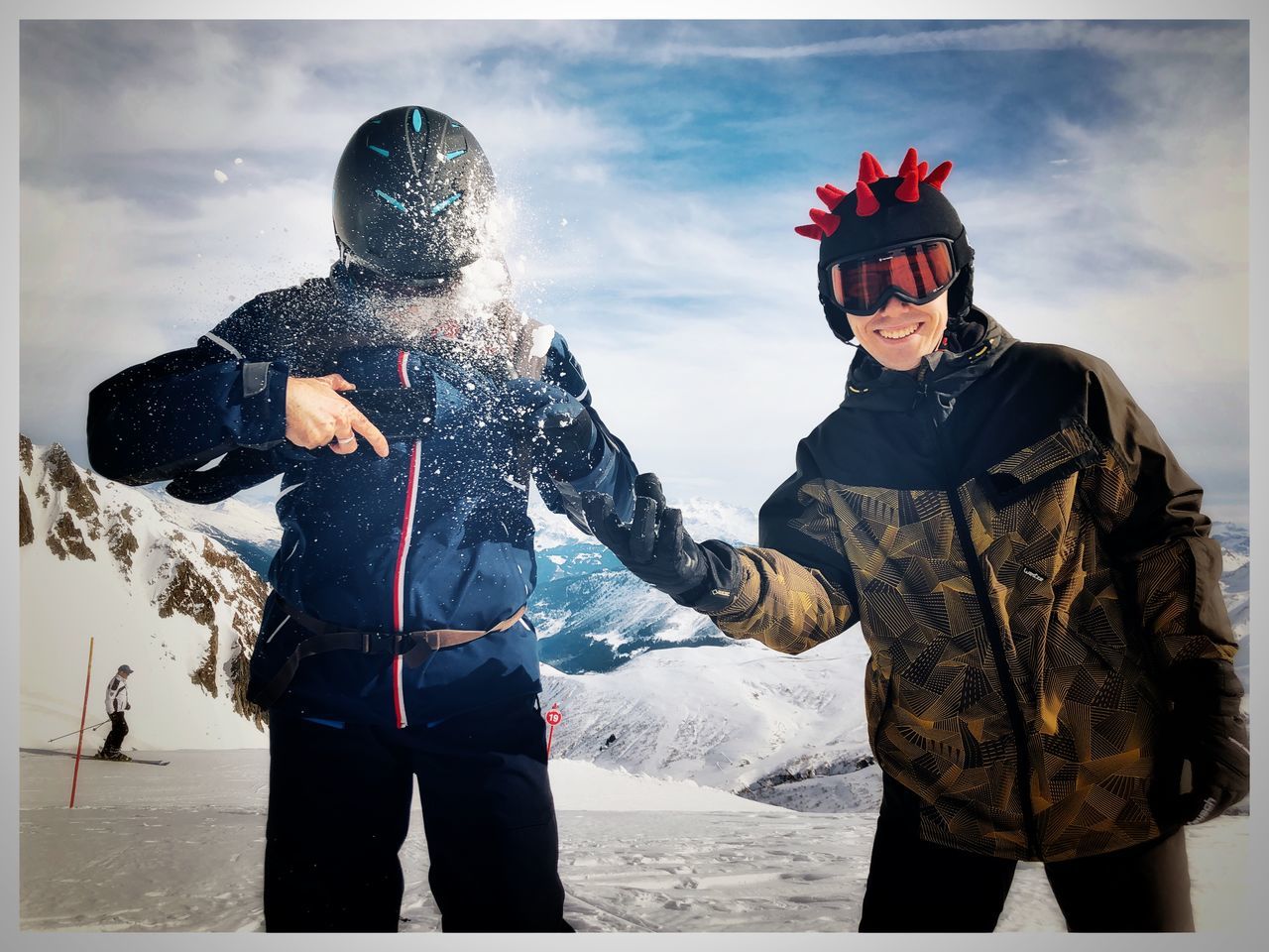 two people, skiing, adult, men, snow, clothing, winter, cold temperature, sports, standing, person, nature, poster, young adult, headwear, sky, togetherness, warm clothing, helmet, sports equipment, day, ski goggles, mountain, three quarter length, front view, outdoors, leisure activity, winter sports, cloud