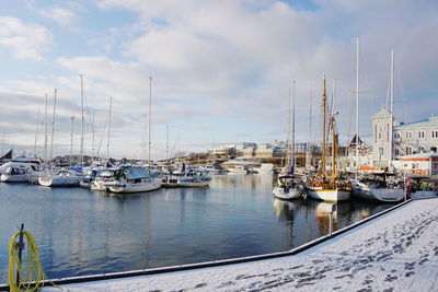 Boats moored at harbor against sky