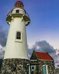 Low angle view of lighthouse by building against sky