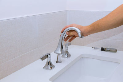 Cropped hand of plumber repairing faucet