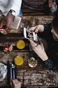 High angle view of woman photographing food through smart phone at table