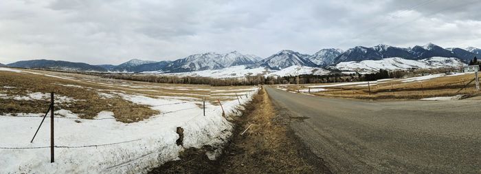 Road amidst snowcapped mountains against sky