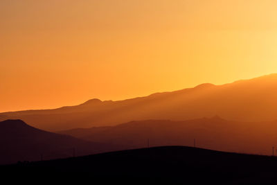 Scenic view of silhouette mountains against orange sky