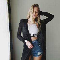 Young woman standing against wall at home