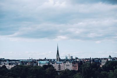 Buildings in city against cloudy sky