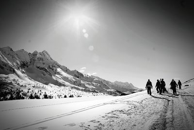 People walking on snowcapped mountain against sky