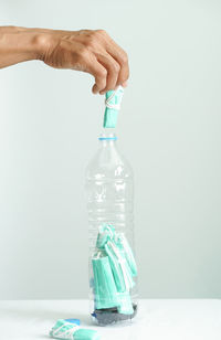 Close-up of hand holding bottle against white background