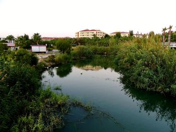 Houses by lake and buildings against sky