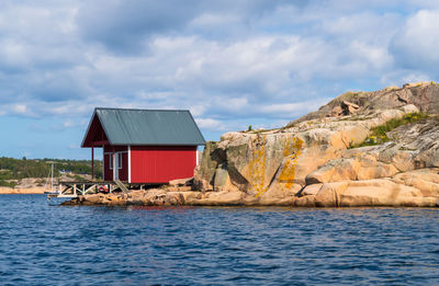 Stilt house by sea against sky