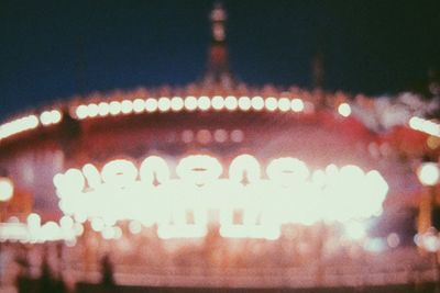 Defocused image of illuminated carousel at night