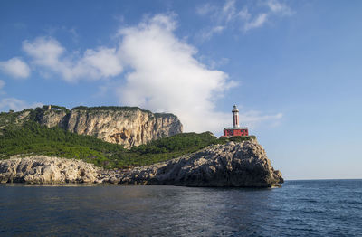 Lighthouse by sea against sky